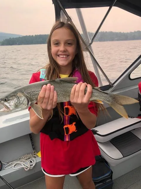YOUNG GIRL HOLDING A LAKE TROUT ON WHITEFISH LAKE